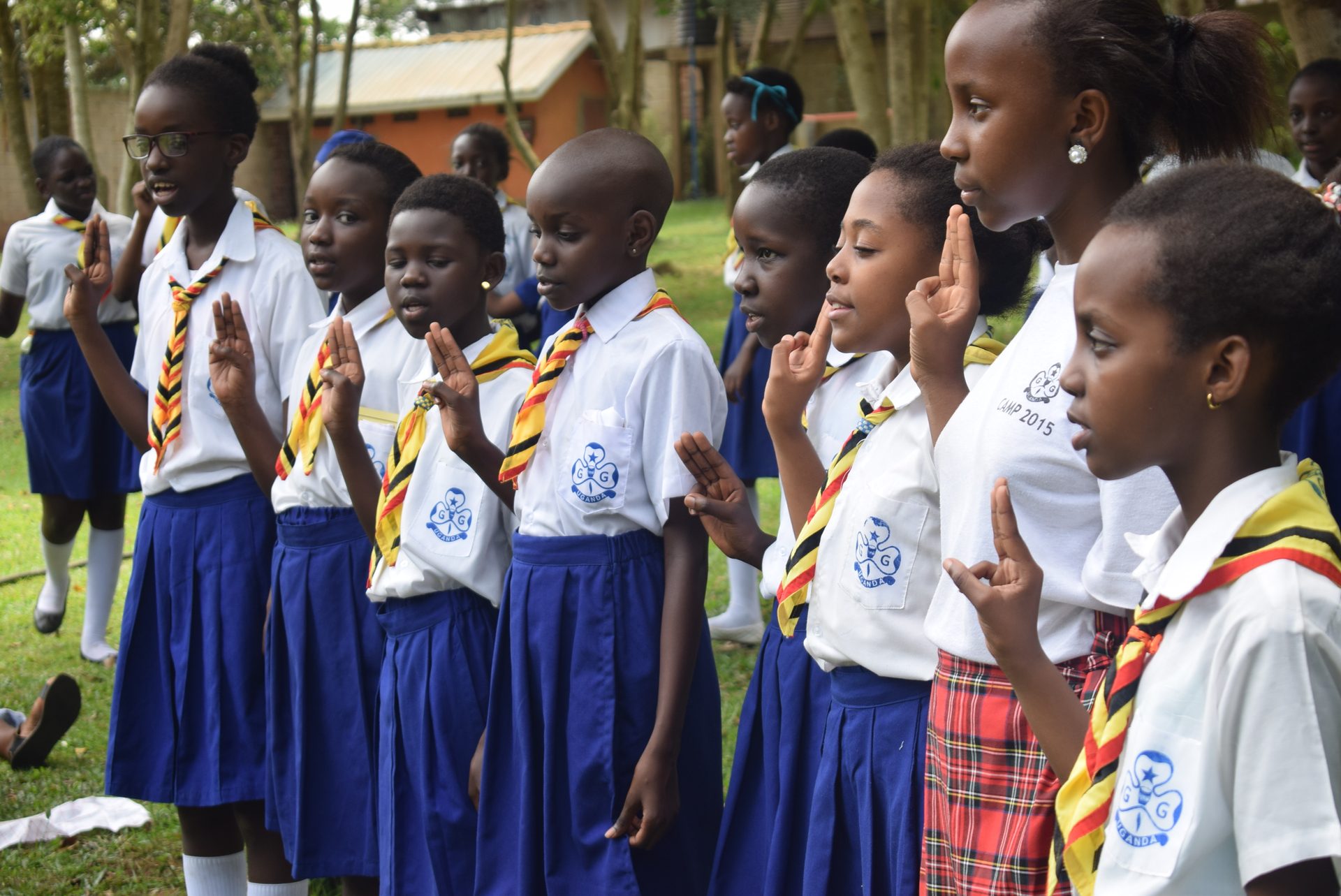 Girl Guides in uniform making the Guide sign during their promise