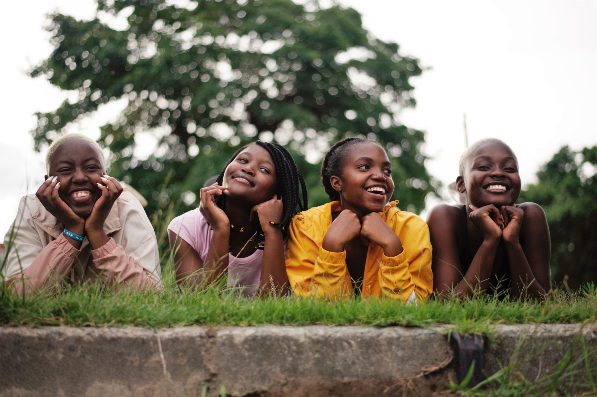 Four young women lying on the grass together, laughing
